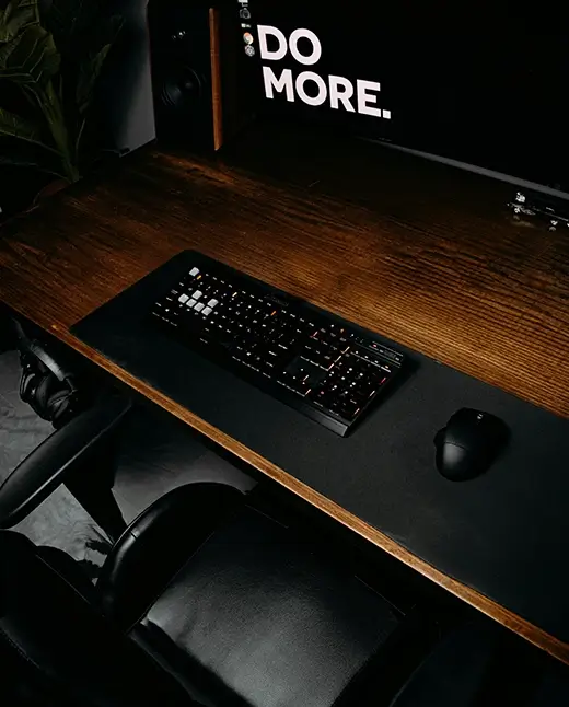 A black computer keyboard resting on a brown wooden desk